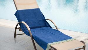 Eine lächelnde Frau legt am Pool ihr Handtuch auf eine Liege.