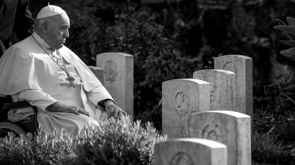 Schwarz-weiß-Foto von Papst Franziskus im Rollstuhl auf einem Friedhof