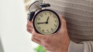 Person dreht an der Uhr, Zeitumstellung