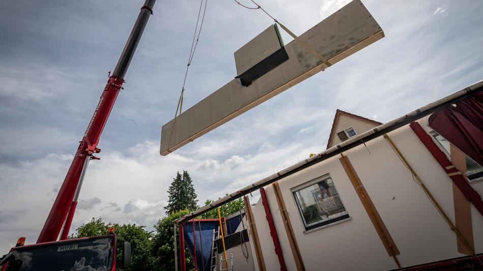 Ein Kran hebt eine vorgefertigte Wand auf einer Baustelle