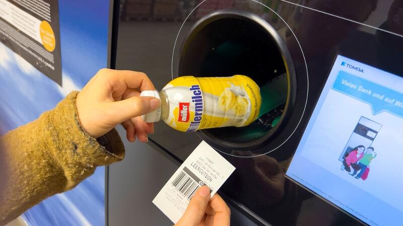 Eine Müllermilchflasche wird in den Pfandautomaten geschoben.