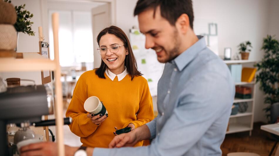 Ein Mann und eine Frau plaudern an der Kaffeemaschine.