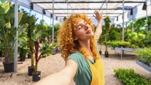 Eine Frau breitet ihre Arme aus und lächelt mit geschlossenem Mund.