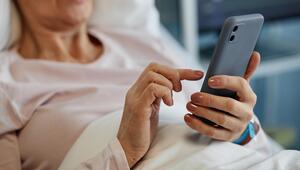 Ältere Frau im Krankenhausbett mit Smartphone in der Hand