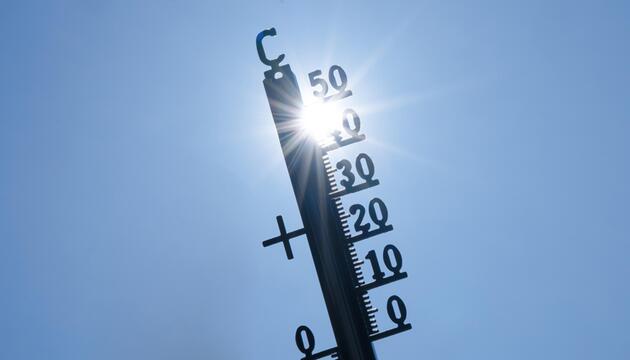 Thermometer, blauer Himmel und Sonnenstrahlen.
