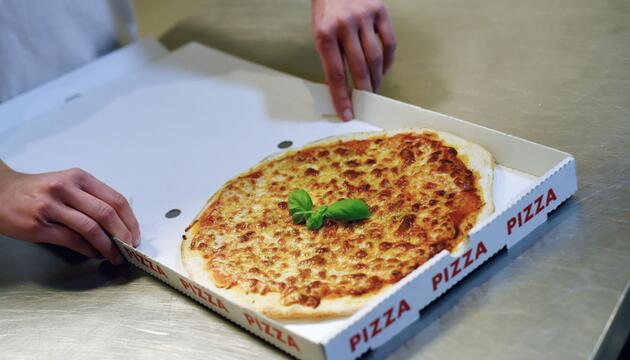 Lieferdienst verpackt eine Pizza in einem Karton