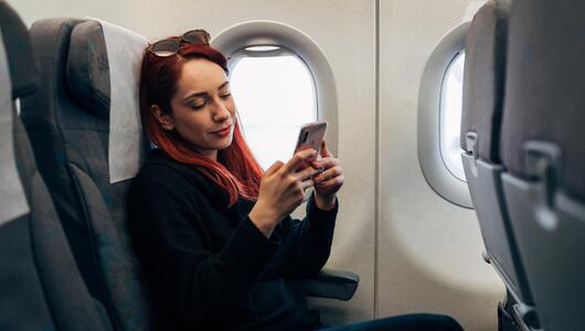 Frau im Flugzeug am Handy
