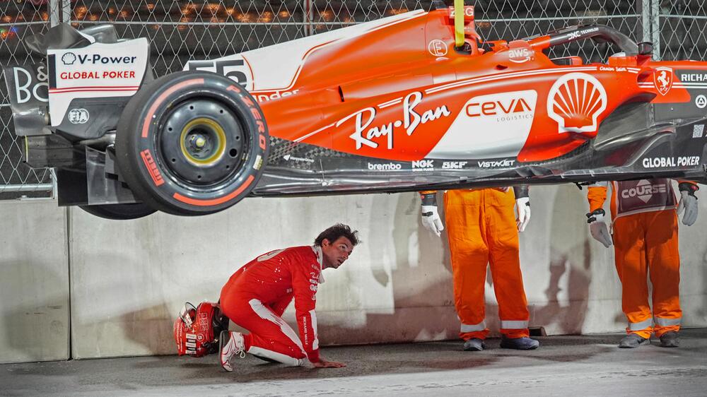 Ferrari-Pilot Carlos Sainz inspiziert seinen defekten Rennwagen