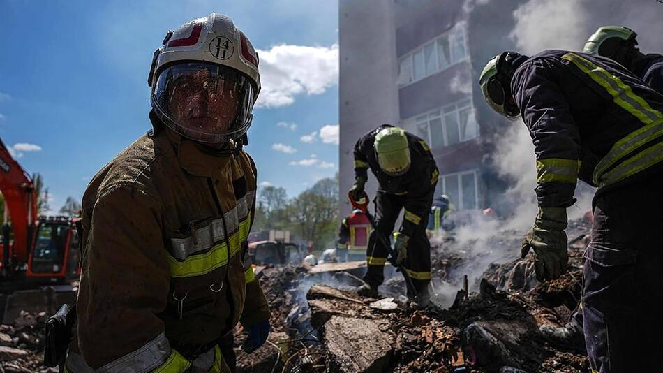 Feuerwehrkräfte auf einem Trümmerhaufen.