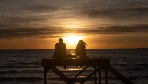 Paar sitzt bei Sonnenuntergang am Strand von Arenal
