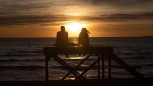 Paar sitzt bei Sonnenuntergang am Strand von Arenal