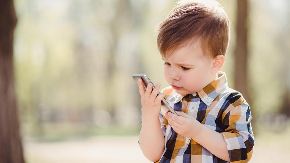 Kleiner Junge, ca 1 Jahr, am Smartphone