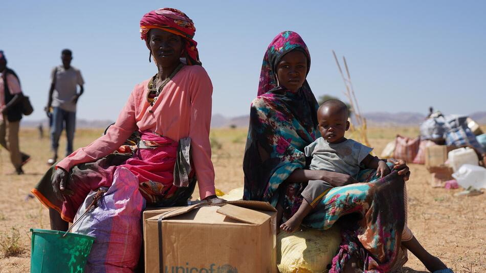 Eine Familie sitzt auf Säcken und Kartons
