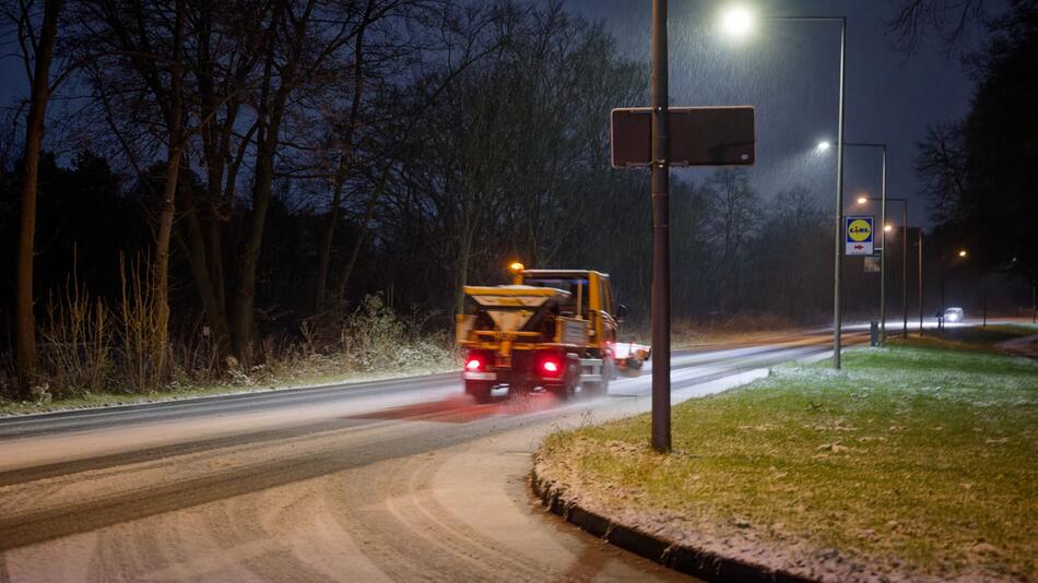 Ein Streufahrzeug in streut auf einer Straße.