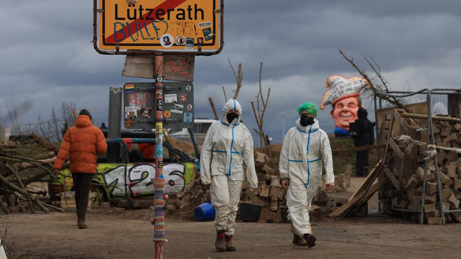 Klimaschutzaktivisten gehen an einem Schild mit der Aufschrift Lützerath vorbei