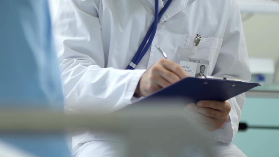 Ein Arzt füllt den Anamnesebogen eines Patienten aus
