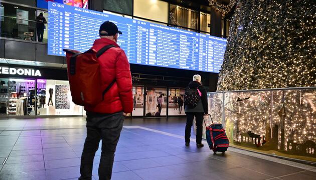 Fahrgäste blicken am Berliner Hauptbahnhof auf die Fahrplananzeige. 