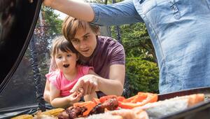 Familie mit Kleinkind grillt im Garten