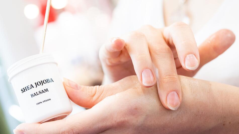 Eine Frau nutzt ein Kosmetikprodukt an der Hand