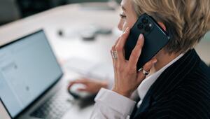 Frau sitzt am Laptop und telefoniert