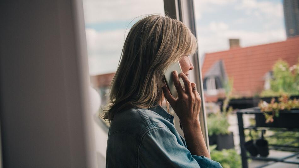 Frau telefoniert am Fenster