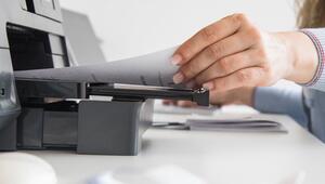 Frau nimmt ein Blatt Papier aus einem Drucker