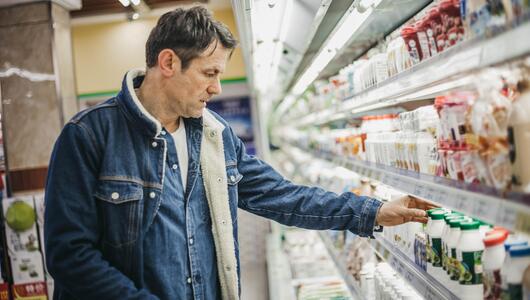 Mann in Supermarkt, der Preise vergleicht. 