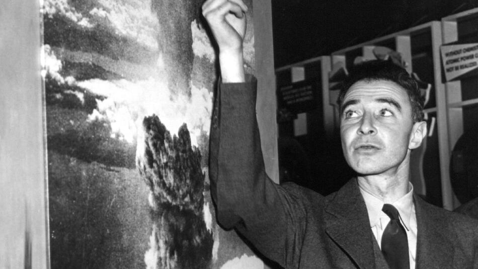 Robert Oppenheimer neben einer Fotografie der Atombombenexplosion.