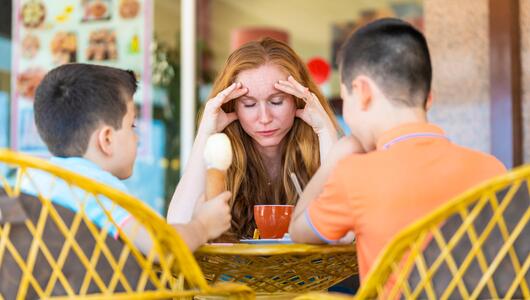 Gestresste Mutter isst mit ihren Kindern Eis