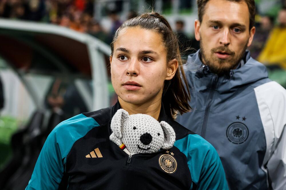 DFB-Spielerin Lena Oberdorf trägt das gehäkelte Maskottchen Waru unter ihrer Jacke.