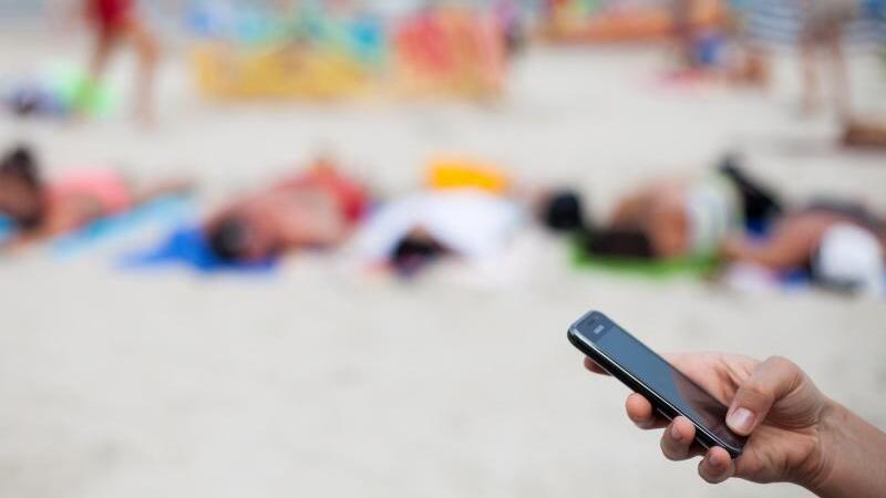 Eine Frau mit Smartphone am Strand