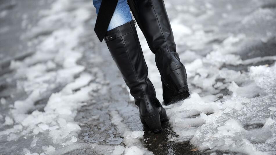 Frau läuft durch nassen Schneematsch