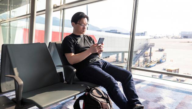 Mann am Flughafen ist am Handy