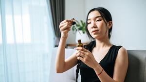 Junge Frau mit schwarzen Haaren, die eine Pipette in der Hand hält. 