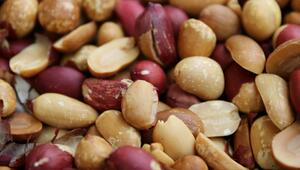 Nahaufnahme von ungeschälten und teilweise geschälten Erdnüssen mit brauner und rötlicher Schale.