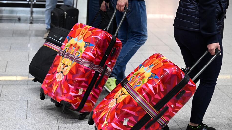 Reisende schieben ihre Koffer am Flughafen München zur Gepäckaufgabe.