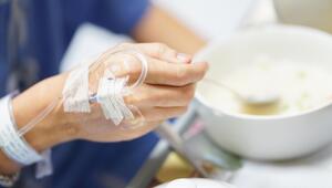 Person in Krankenhaus mit Infusion isst Suppe