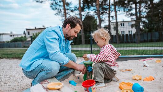 Vater spielt mit Kind im Sandkasten