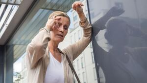 Frau mit Schwindelanfall stützt sich an einer Hauswand ab