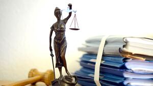 Unterlagen liegen neben einer Nachbildung der Justitia