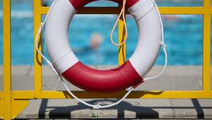 Ein Schwimmring hängt in einem Freibad an einem Geländer.