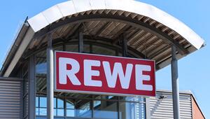 Ein großes Schild mit "REWE"-Aufschrift am Gebäude.