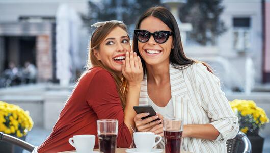 Junge Frauen lachen im Café und Flüstern