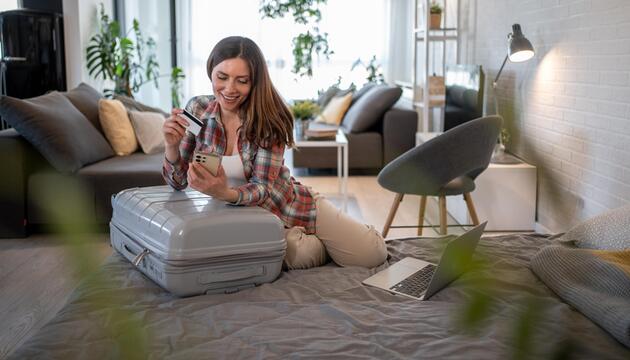 Frau, die Reiseunterkünfte online mit Kreditkarte und Smartphone bucht