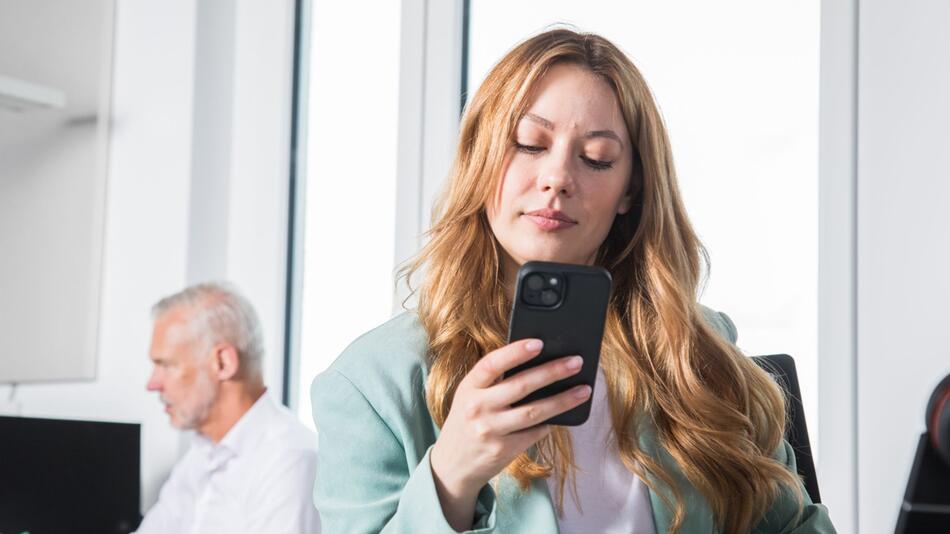 Eine Frau mit Smartphone am Arbeitsplatz