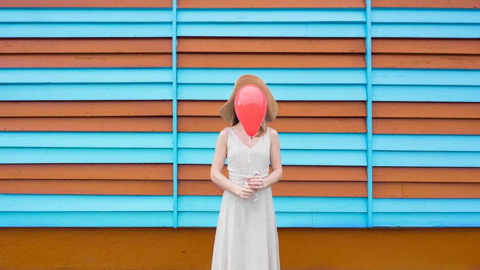 Eine junge Frau hält sich einen Luftballon vors Gesicht