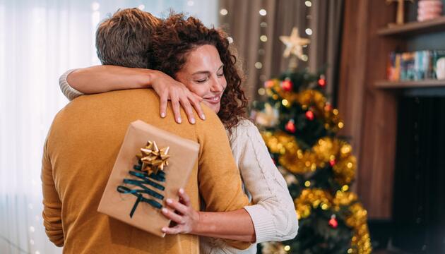 Frau umarmt einen Mann dankbar mit Geschenk in der Hand