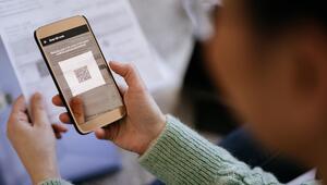Ältere Frau scannt QR-Code auf einem Brief