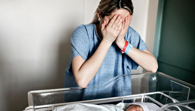 Eine Mutter am Bett mit ihrem Neugeborenen
