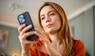 Frau schaut genervt auf ihr Smartphone